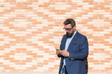 İş adamı dışarıda duvara karşı dururken akıllı telefon kullanıyor..