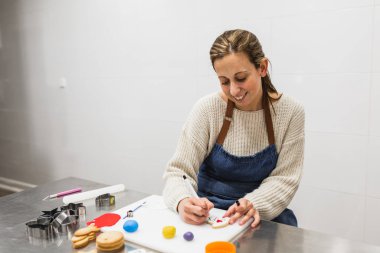 Pozitif ve mutlu kadın pastanede kurabiye süslüyor.