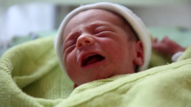 Close up view of a tiny newborn baby crying and moving around while covered and wrapped in blankets. — Vídeo de Stock