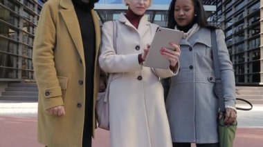 İş arkadaşları ofis binası dışında iş hakkında konuşurken birlikte dijital tablet kullanıyorlar..