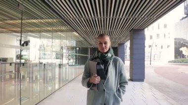 Finans bölgesinde ofis binasının dışında yürürken kameraya bakan bir iş kadını..