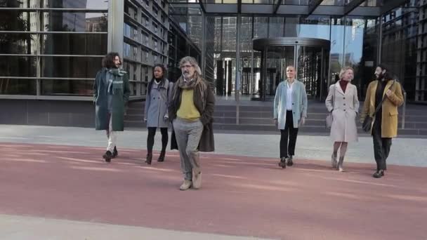 Group of co-workers walking together leaving the office building in the financial district. — Stockvideo