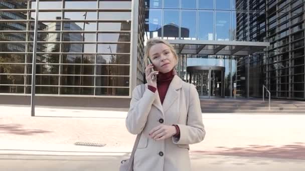 Professional businesswoman talking on the phone while walking on the street after leaving the office. — Stockvideo