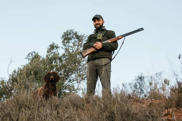 Porträt eines jungen Jägers, der mit seinem Hund in die Kamera blickt — Stockfoto