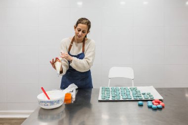 Pasta dükkanında makaronları doldurmak için elinde boru torbası olan pasta şefinin ön görüntüsü..