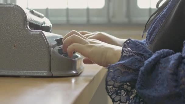 視覚障害者のための点字文字符号化を書くために使用される単純な機械であるヴィンテージの点字タイプライターを使用して 障害者の女性の手のクローズアップハンドヘルドショット — ストック動画