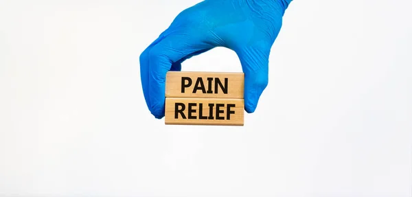痛みの救済記号 青い手袋の医師の手は言葉で木製のブロックを保持痛みの救済 美しい白い背景 医療と痛みの救済の概念 — ストック写真