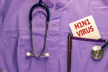 H1N1 virüs sembolü. Tıbbi üniforma, üzerinde H1N1 virüsü yazan beyaz kart, metal kalem ve stetoskop. Tıbbi, H1N1 virüs konsepti.