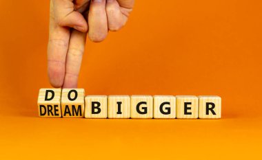 Hayal et ve daha büyük bir sembol yap. İş adamı ahşap küplere dönüşür ve daha büyük hayaller kurmak için kelimeleri değiştirir. İş, hayal ve daha büyük bir konsept. Güzel turuncu arkaplan, kopyalama alanı.