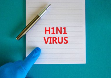 H1N1 virüs sembolü. Beyaz notta H1N1 virüsü, güzel mavi arkaplan, doktor eli mavi eldiven ve metal kalem var. Tıbbi, H1N1 virüs konsepti.