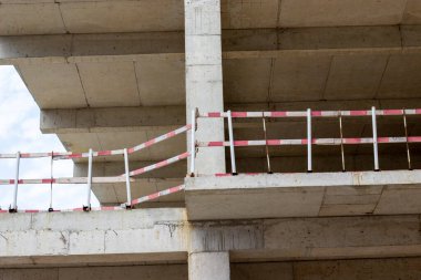 Modern bir binanın ön cephesi yapım aşamasında. İnşaat halindeki çok katlı bir binaya yakın çekim. Evin duvarları çalışma ve mimari sürecinde..