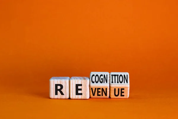 Revenue and recognition symbol. Businessman turned cubes and changed the word revenue to recognition. Beautiful orange table, orange background. Business, revenue and recognition concept. Copy space.