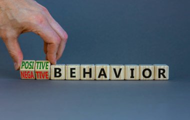 Pozitif ya da negatif davranış sembolü. İşadamı küplere dönüşüyor, kelimeleri değiştiriyor olumsuz davranışları olumlu davranışlara dönüştürüyor. Gri arkaplan, kopyalama alanı. Psikoloji, pozitif ya da negatif davranış konsepti.