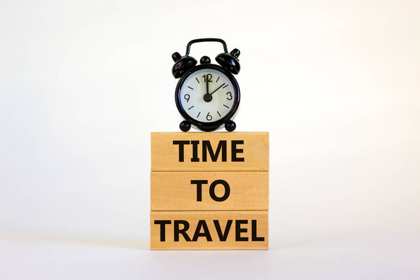 Time to travel symbol. Wooden blocks with concept words 'Time to travel'. Black alarm clock. Beautiful white background. Business and time to travel concept. Copy space.