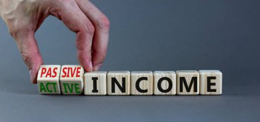 Passive or active income symbol. Businessman turns wooden cubes and changes words passive income to active income. Beautiful grey background, copy space. Business, passive or active income concept. clipart