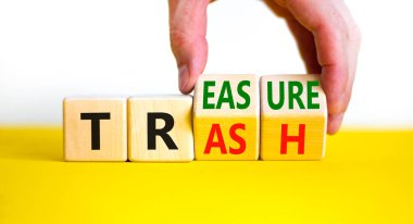 Çöpten hazine sembolüne. İş adamı küpleri dönüştürür ve çöp kelimesini hazineye çevirir. Güzel sarı masa, beyaz arka plan. İş, çöpten hazine konseptine. Boşluğu kopyala.