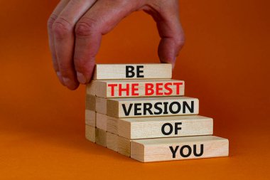 Sembolünün en iyi versiyonu. Sözcüklerle tahta bloklar turuncu arkaplandaki en iyi versiyonun ol, kopyalama uzayı. İşadamı eli. İş, senin en iyi versiyonun..