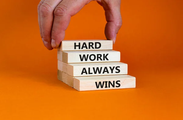 努力工作总能赢得象征 在漂亮的橙色背景上的木块上 努力工作总能赢 的概念词 商人的手 激励和努力工作总能赢得理念 — 图库照片