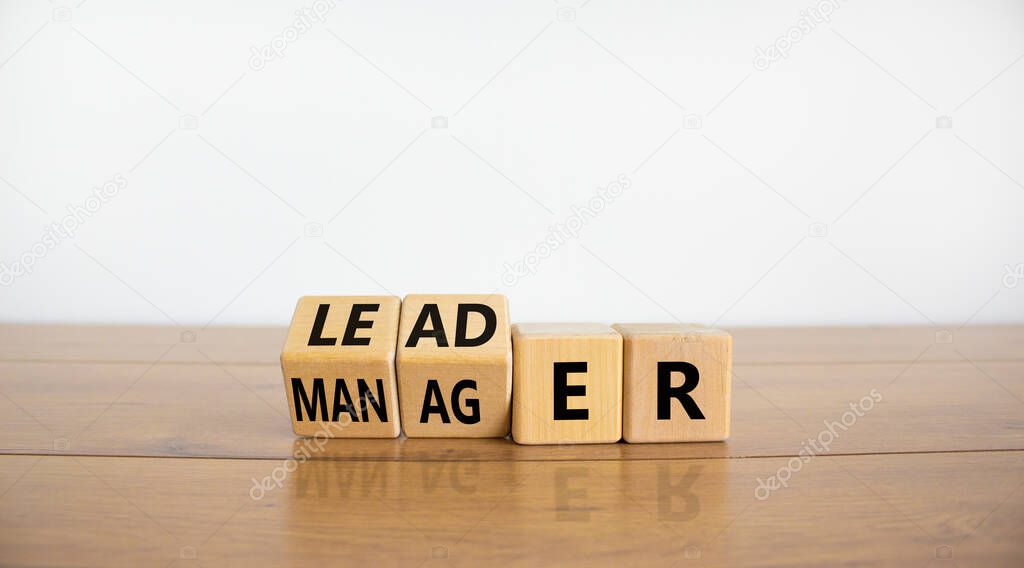 Manager versus leader symbol. Turned wooden cubes and changed the word 'manager' to 'leader'. Beautiful wooden table, white background, copy space. Business and manager versus leader concept.