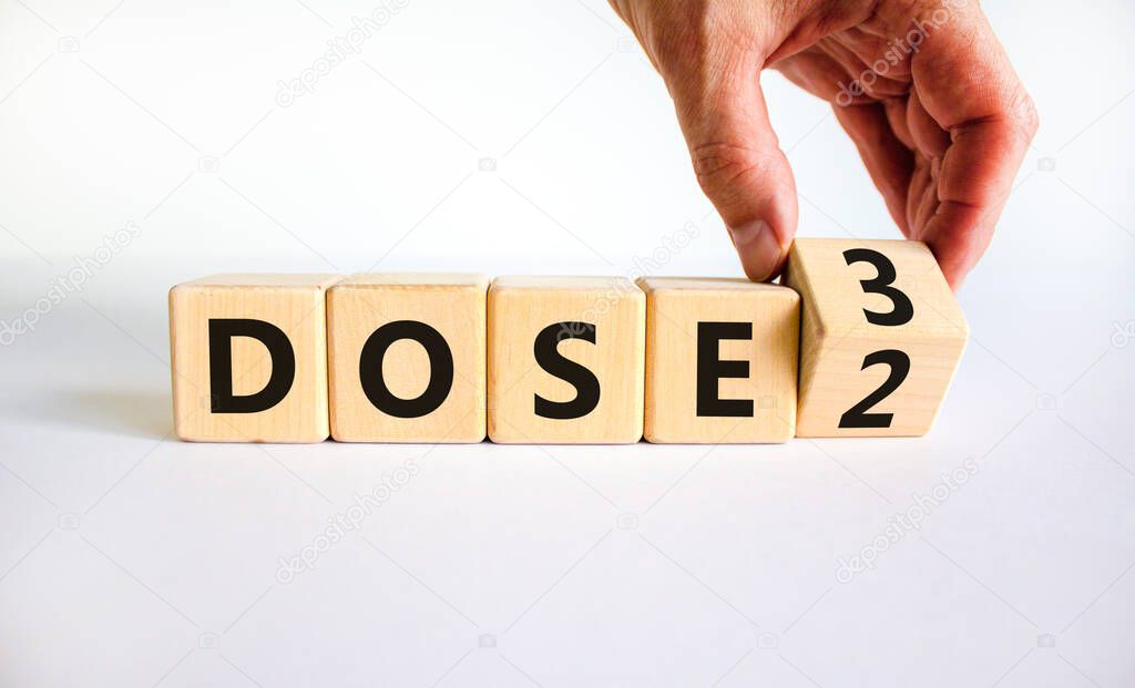 Covid-19 booster dose vaccine shot symbol. Doctor turns cubes and changes words 'dose 2' to 'dose 3'. Beautiful white table, white background, copy space. Covid-19 booster dose vaccine shot concept.