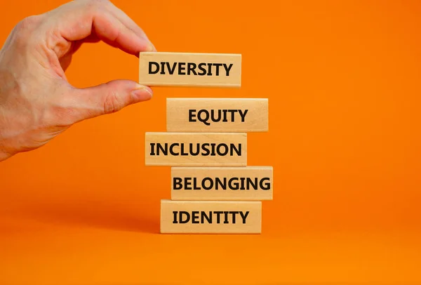 多様性 公平性 包摂性 帰属性 アイデンティティシンボル 単語の多様性 公平性 美しいオレンジの背景にアイデンティティを持つ木製のブロック ビジネス インクルージョンの概念 — ストック写真