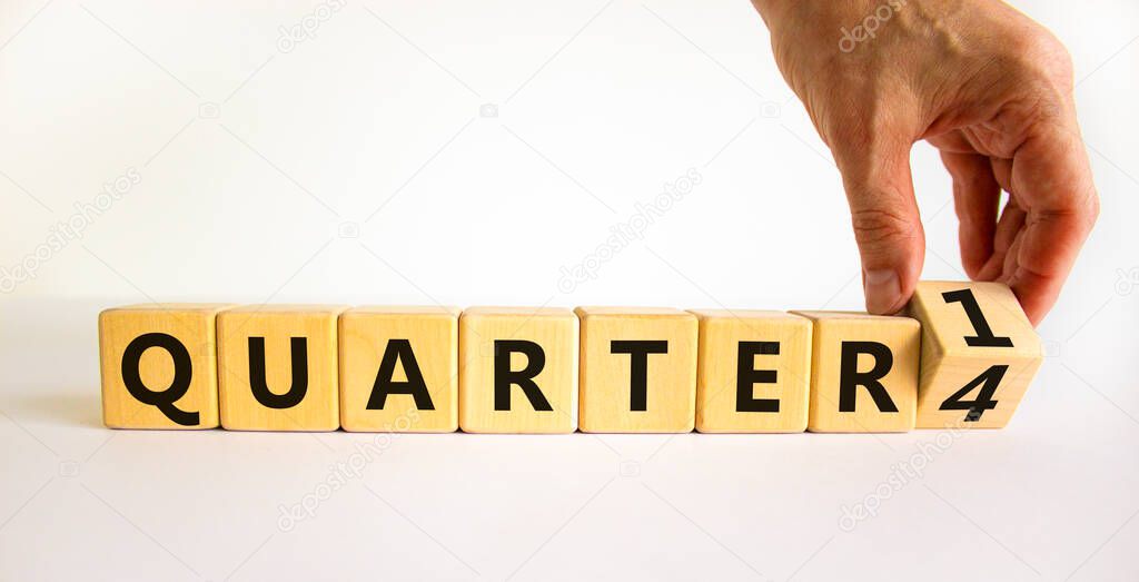 From 4th to 1st quarter symbol. Businessman turns a cube and changes words 'quarter 4' to 'quarter 1'. Beautiful white table, white background. Business, happy 1st quarter concept, copy space.