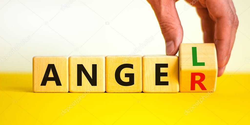 Having anger or being an angel. Businessman turns a wooden cube and changes the word anger to angel. Beautiful white background. Business and anger or angel concept. Copy space.