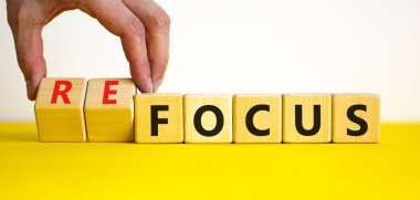 Odaklan ya da tekrar odaklan. İş adamı ahşap küplere dönüşür ve odaklanma kelimesini yeniden odaklamak için değiştirir. Güzel sarı masa, beyaz zemin, kopyalama alanı. İş, odaklanma veya yeniden odaklanma kavramı.