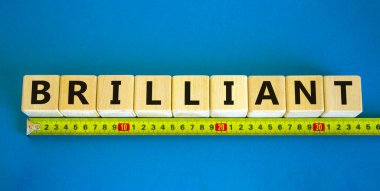 Parlak sembol. Ahşap küplerin üzerindeki konsept kelime dahice. Sarı cetvel. Güzel mavi masa, mavi arka plan. İş ve parlak konsept. Boşluğu kopyala.