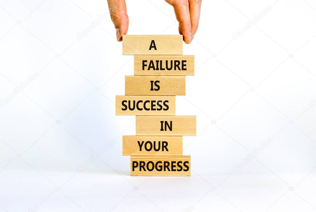 Failure or success symbol. Wooden blocks with words A failure is success in your progress. Beautiful white background, copy space. Businessman hand. Business, failure or success concept.