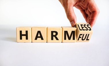 Zararsızdan zararsıza. İş adamı ahşap küpü değiştiriyor ve zararsız kelimesini değiştiriyor. Güzel beyaz masa, beyaz arka plan. İş ve zararsız ya da zararsız bir kavram. Boşluğu kopyala.