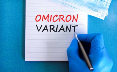 Yeni covid-19 omikron varyant türü sembolü. Beyaz notlu mavi eldiven verin. Omicron değişkeni kavramsal kelimeler. Metalik kalem. Tıbbi ve COVID-19 omikron varyant türü konsepti. Boşluğu kopyala.