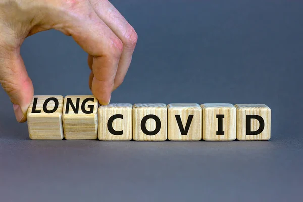 Uzun renkli bir sembol. Doktor ahşap küpleri döndürür ve kelimeleri 'covid' yerine 'covid' kullanır. Güzel gri masa, gri arkaplan, kopyalama alanı. Tıbbi, covid-19 salgın uzun covid konsepti.