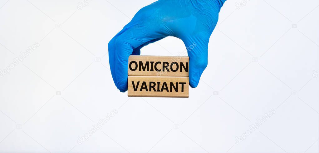 Covid-19 new omicron strain symbol. Hand in blue glove, wooden blocks, words Omicron variant. Beautiful white background. Copy space. Medical and COVID-19 new omicron strain variant virus concept.
