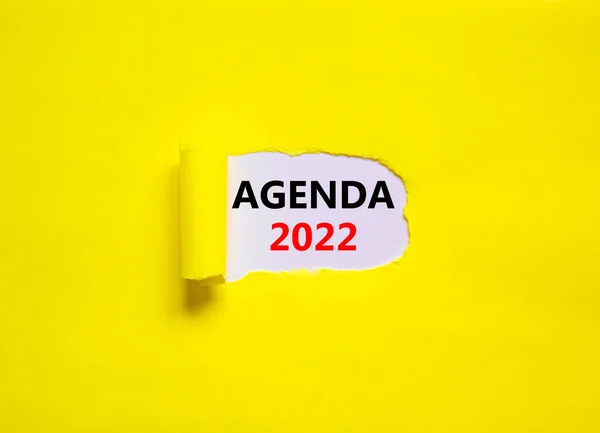2022 agenda new year symbol. Words '2022 agenda' appearing behind torn yellow paper. Beautiful yellow background. Business, 2022 agenda new year concept, copy space.