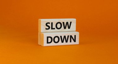 Sembolü yavaşlatma zamanı. Kavramsal kelimeler güzel bir turuncu arka planda ahşap bloklarda yavaşlar. İş ve konsepti yavaşlat. Boşluğu kopyala.