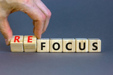 Odaklan ya da tekrar odaklan. İş adamı ahşap küplere dönüşür ve odaklanma kelimesini yeniden odaklamak için değiştirir. Güzel gri masa, gri arka plan, kopyalama alanı. İş, odaklanma veya yeniden odaklanma kavramı.