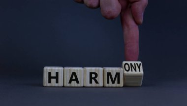 Zarardan armoniye. İş adamı ahşap küpü döndürür ve kelime zararını ahenge çevirir. Güzel gri masa, gri arka plan. İş ve zarar ya da uyum kavramı. Boşluğu kopyala.