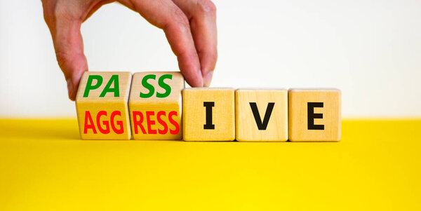 Пассивный или агрессивный символ. Бизнесмен превращает деревянные кубики и превращает слово пассивное в агрессивное. Красивый белый фон, пространство для копирования. Бизнес, психологическая пассивная агрессия.