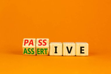 Pasif ya da iddialı bir sembol. Tahta küpler, pasif kavramını kendine güvenen olarak değiştirdi. Güzel turuncu masa, turuncu arka plan, fotokopi alanı. İş, psikolojik pasif iddialı konsept.