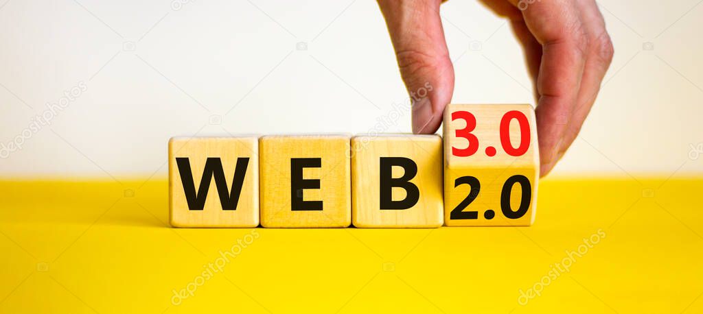 WEB 2.0 or 3.0 symbol. Businessman turns a wooden cube and changes words WEB 2.0 to WEB 3.0. Beautiful yellow table, white background, copy space. Business, technology and WEB 2.0 or 3.0 concept.