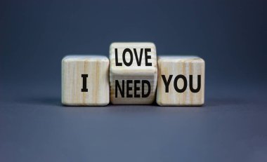 I love and need you symbol. Psychologist turns wooden cubes and changes words I need you to I love you. Beautiful grey table grey background, copy space. Psychological i love and need you concept.