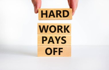 Hard work pays off symbol. Concept words Hard work pays off on blocks. Businessman hand. Beautiful white table, white background, copy space. Business and hard work pays off concept.