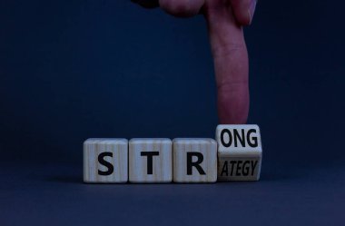 Strong strategy symbol. Businessman turns a wooden cube with words strong strategy. Beautiful grey table, grey background, copy space. Business and strong strategy concept.