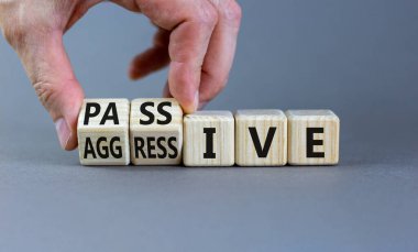 Pasif ya da agresif sembol. İş adamı ahşap küplere dönüşür ve pasif kelimesini agresifliğe çevirir. Güzel gri arkaplan, kopyalama alanı. İş, psikolojik pasif agresif konsept.