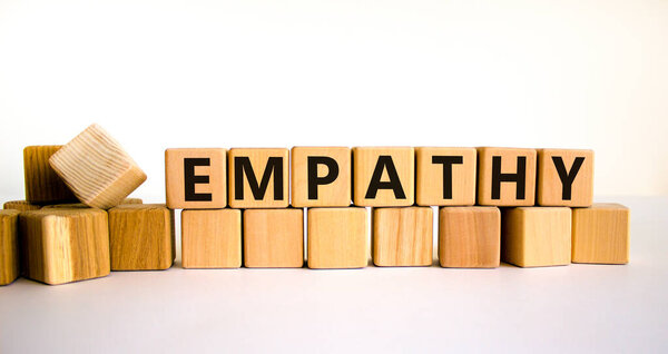 Символ сочувствия. Понятие "эмпатия" на деревянных кубиках. Красивый белый стол, белый фон, пространство для копирования. Концепция бизнеса, психологии и эмпатии.