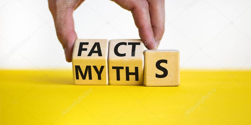 Facts or myths symbol. Businessman turns wooden cubes and changes the word myths to facts. Beautiful yellow table, white background, copy space. Business and facts or myths concept.