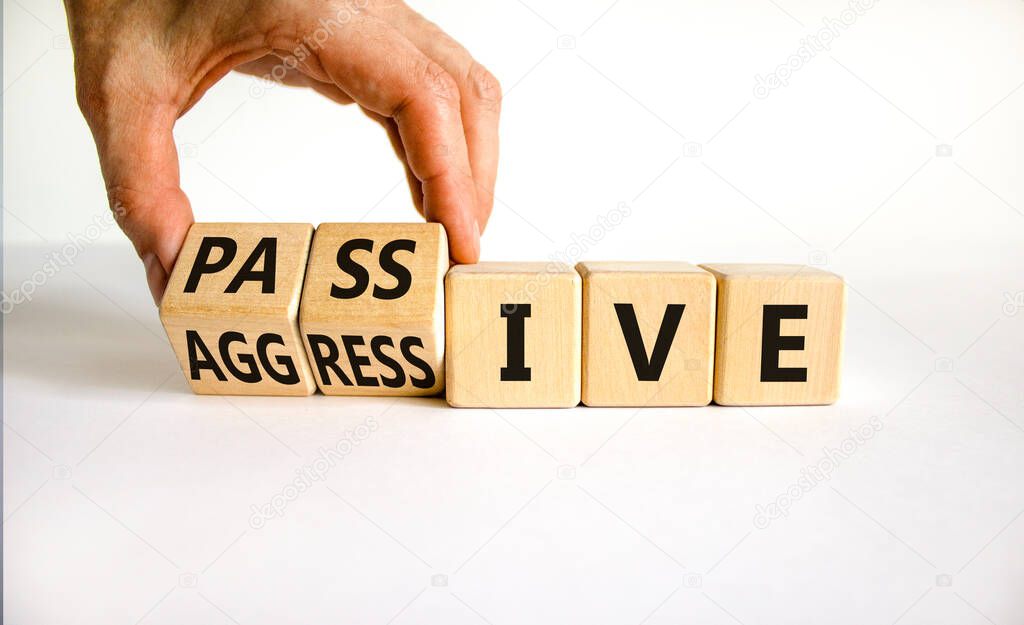 Passive or aggressive symbol. Businessman turns wooden cubes and changes the word passive to aggressive. Beautiful white background, copy space. Business, psychological passive aggressive concept.