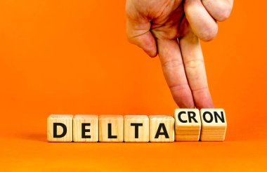 Covid-19 delta ve deltacron sembolü. Doktor küpleri döndürür ve delta kelimesini deltakron olarak değiştirir. Güzel turuncu arka plan. Tıbbi, covid-19 Corona delta ve deltacron konsepti. Boşluğu kopyala.