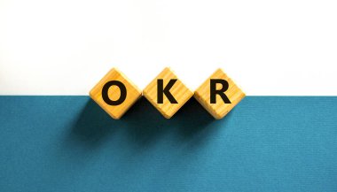OKR, hedefler ve anahtar sonuç sembolü. OKR hedefleri ve güzel beyaz bir zemin üzerinde tahta küplerin anahtar sonuçları kavramsal sözcüklerdir. İş OKR hedefleri ve temel sonuç kavramı. Boşluğu kopyala.